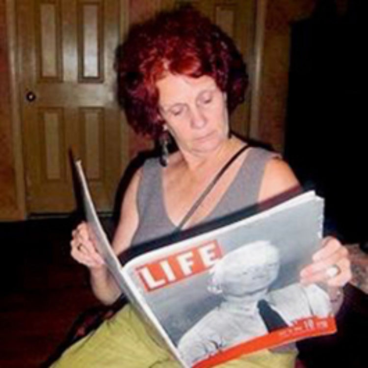 Catherine Ladnier, a white woman with red hair, reading an old issue of LIFE magazine