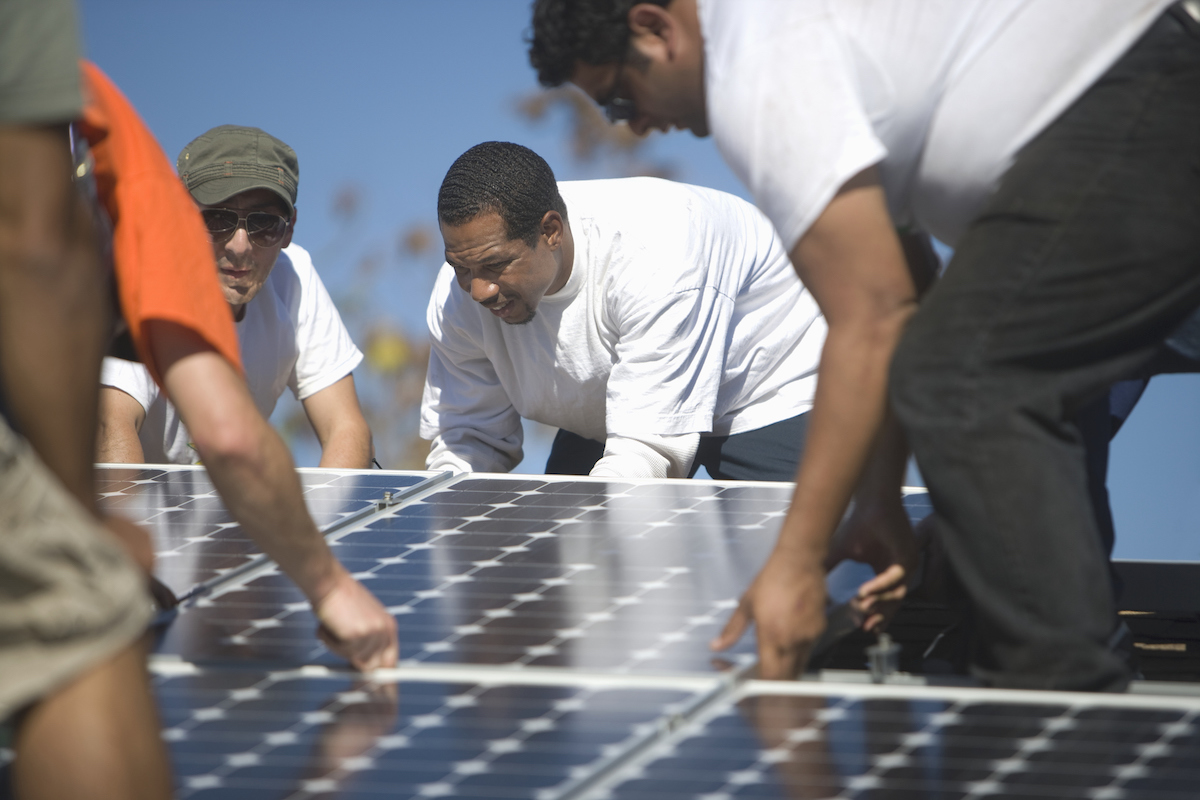 group of men laying down a large solar panel