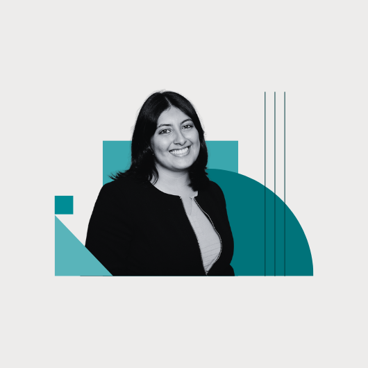 A woman with dark hair, wearing a light top and dark jacket, smiles at the camera. Geometric teal shapes and lines decorate the background.