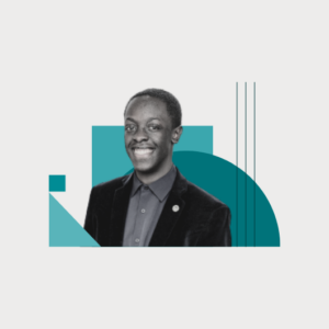 A smiling man in a dark blazer and shirt stands in front of teal geometric shapes on a white background.