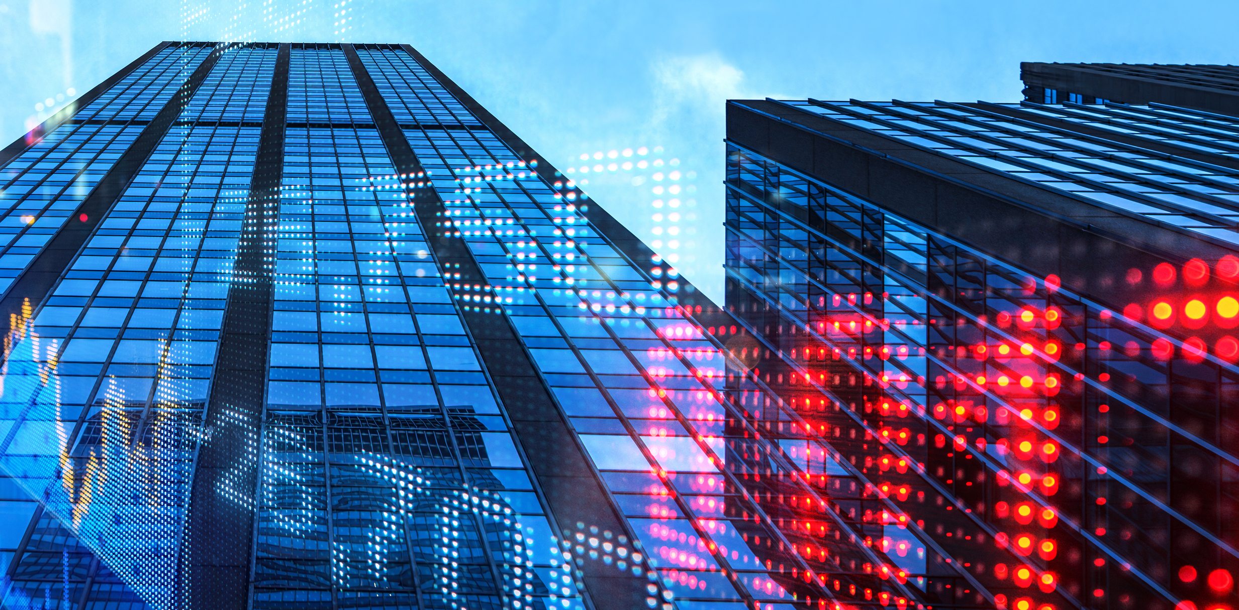 Two glass skyscrapers against a blue sky, overlaid with glowing digital stock market charts and data points.